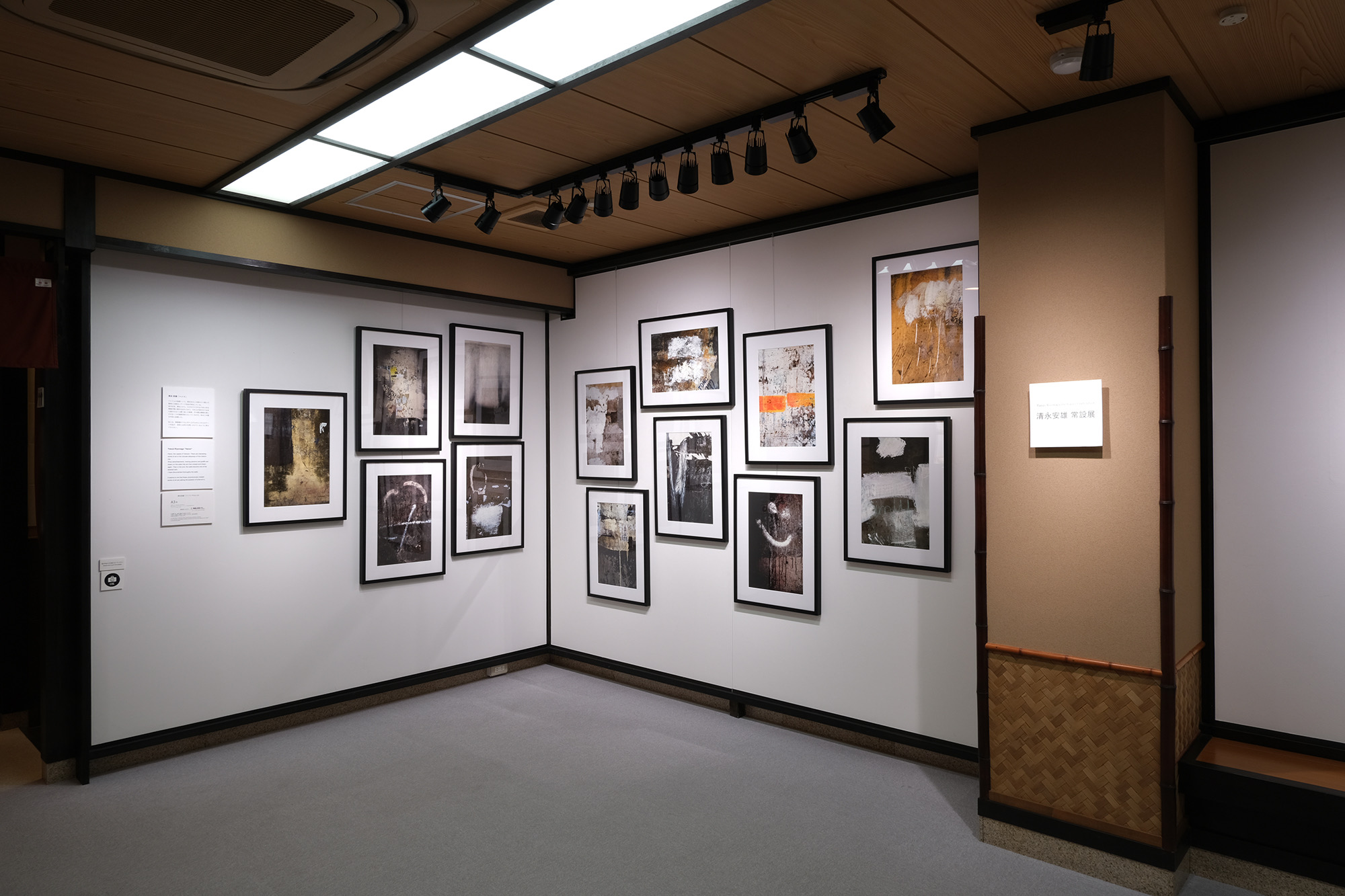 1F展示室。モノクロ作品が密に架かる壁